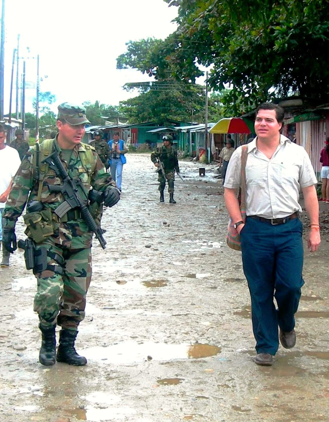 Alejandro Arbeláez A. camina por la calle destapada de un pueblo junto a un soldado, en su época en el Ministerio de Defensa