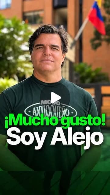 Alejandro Arbeláez A., con camiseta «Modo antioqueño», frente a un edificio de ladrillo con la bandera de Colombia; texto «¡Mucho gusto! Soy Alejo»